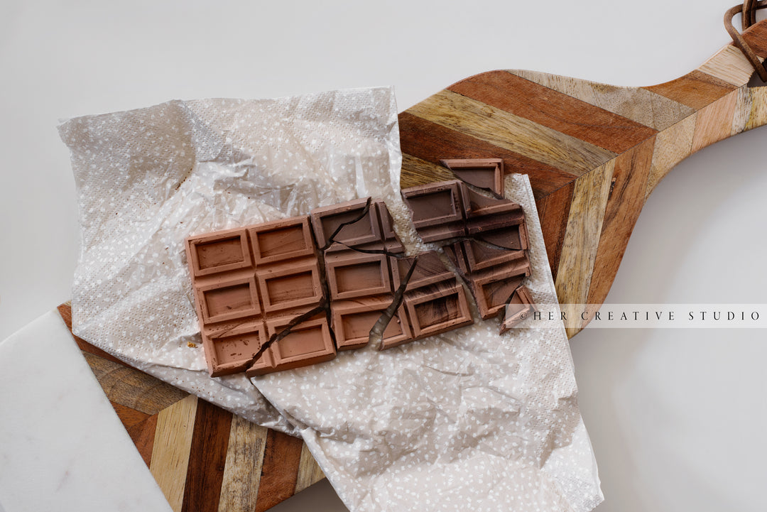 Broken Chocolate on Cutting Board. Digital Image.