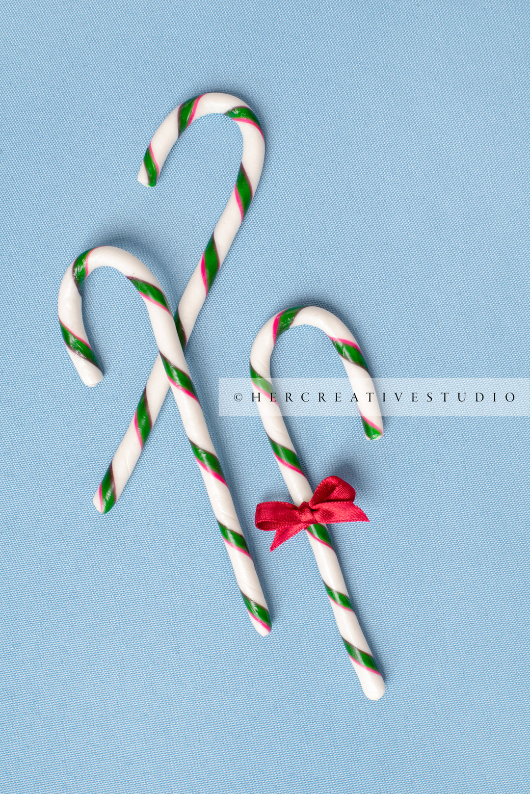 Three Candy Cane with Red Bow on Sky Blue Background