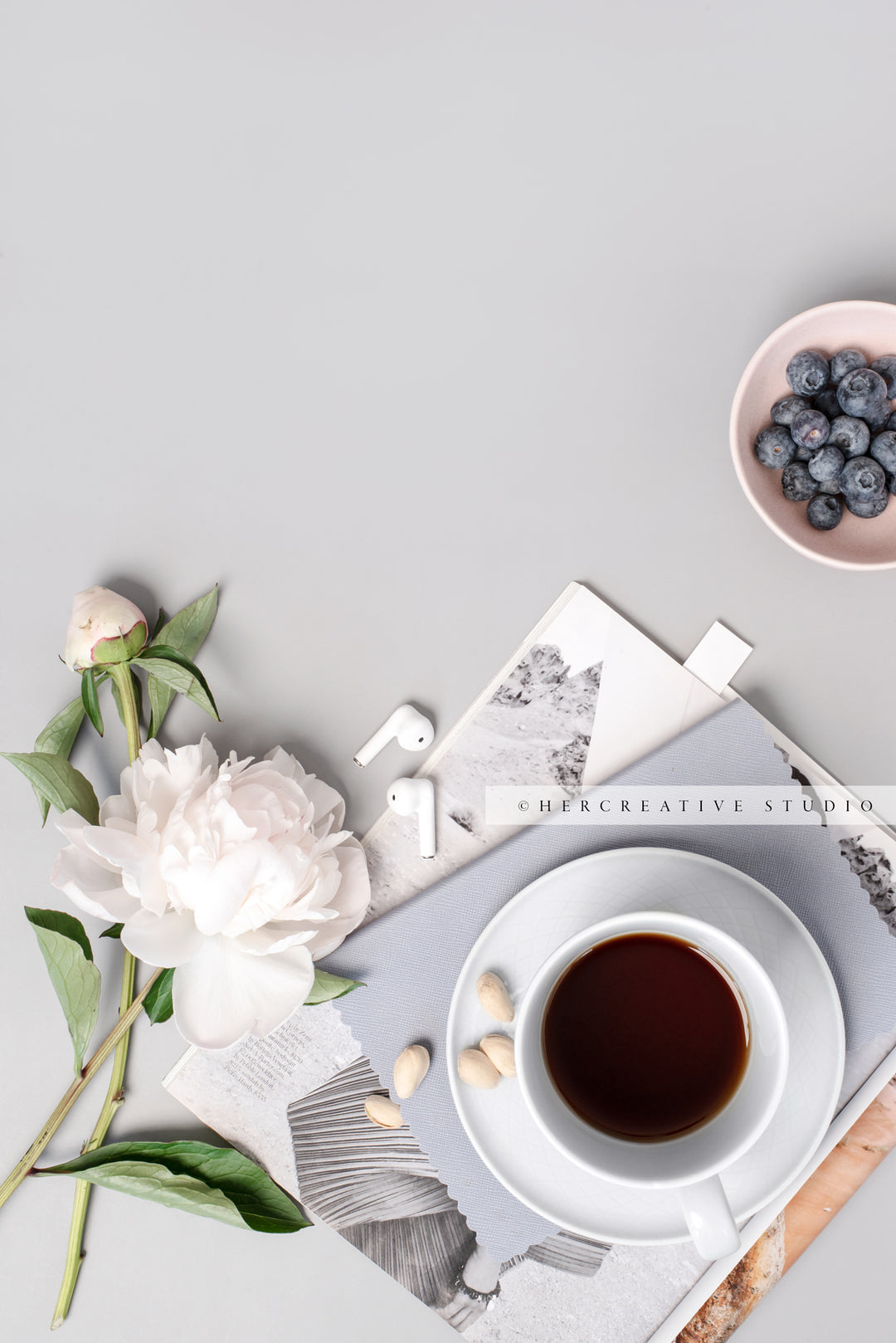 Berries, Peony and Earbuds on Grey Workspace. Stock Image