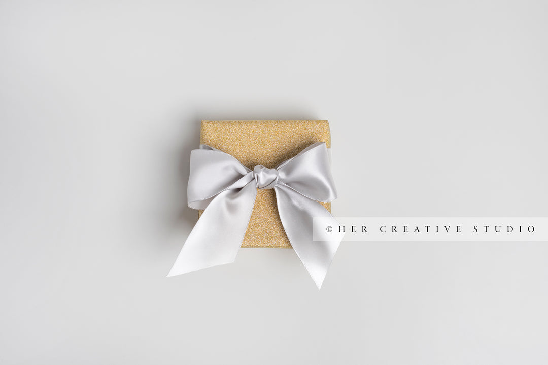 Gold Gift with Silver Grey Ribbon on Grey Background