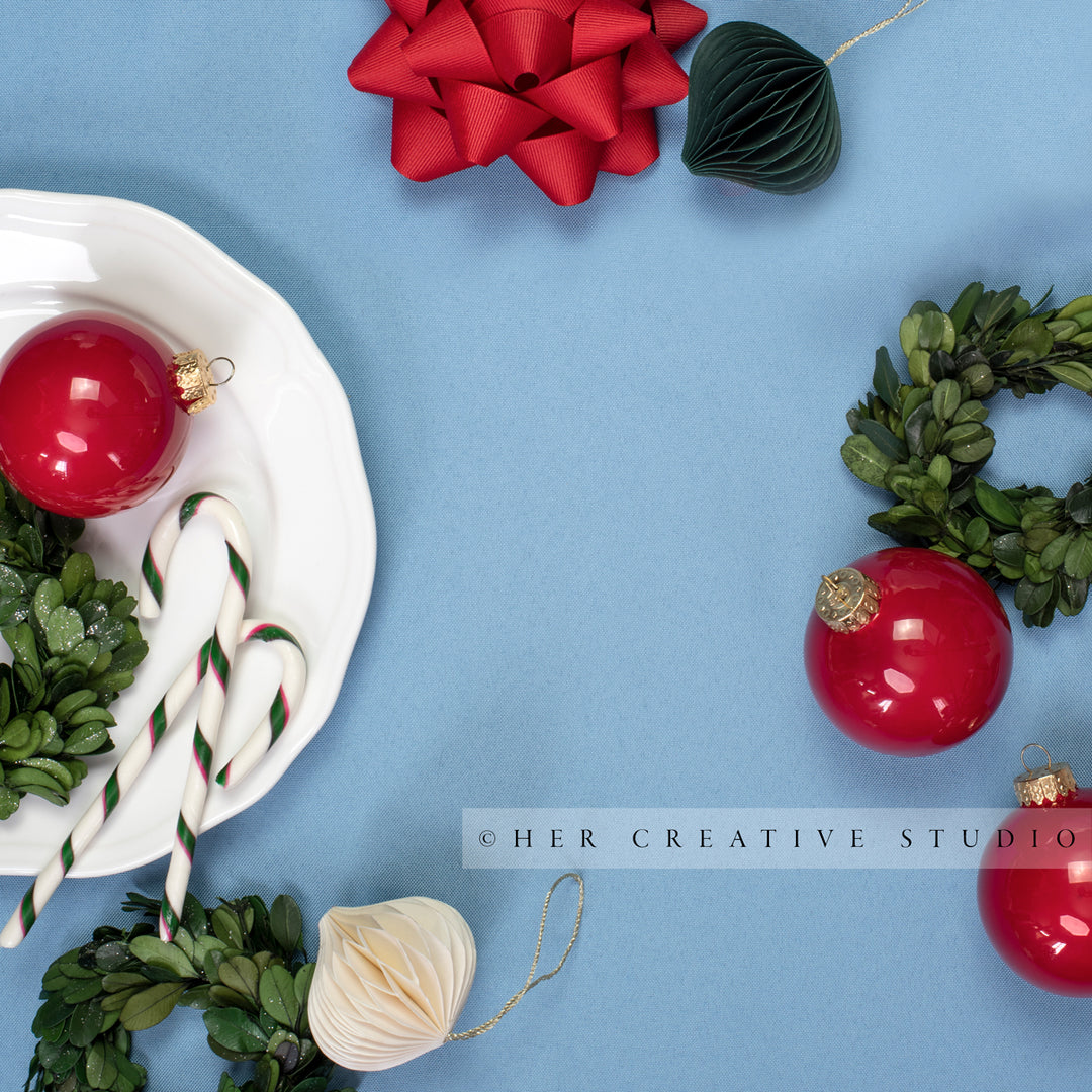 Holiday Ornaments & Mini Wreath Flatlay on Sky Blue Background