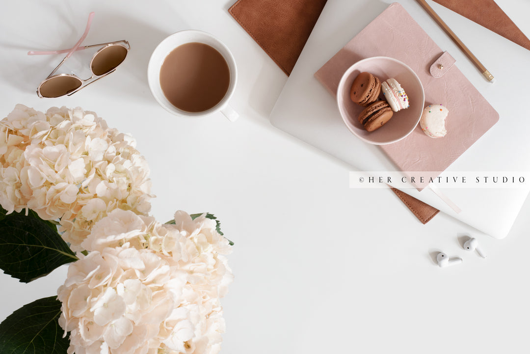 Coffee, Hydrangea & Macarons on White Workspace. Digital Image.