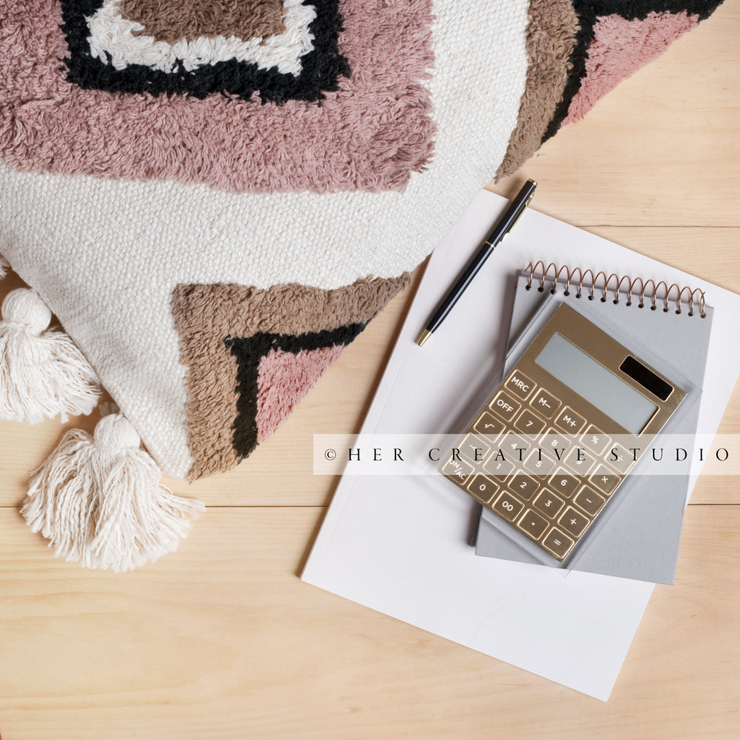Pillow & Calculator on Wood Floor, Styled Stock Image