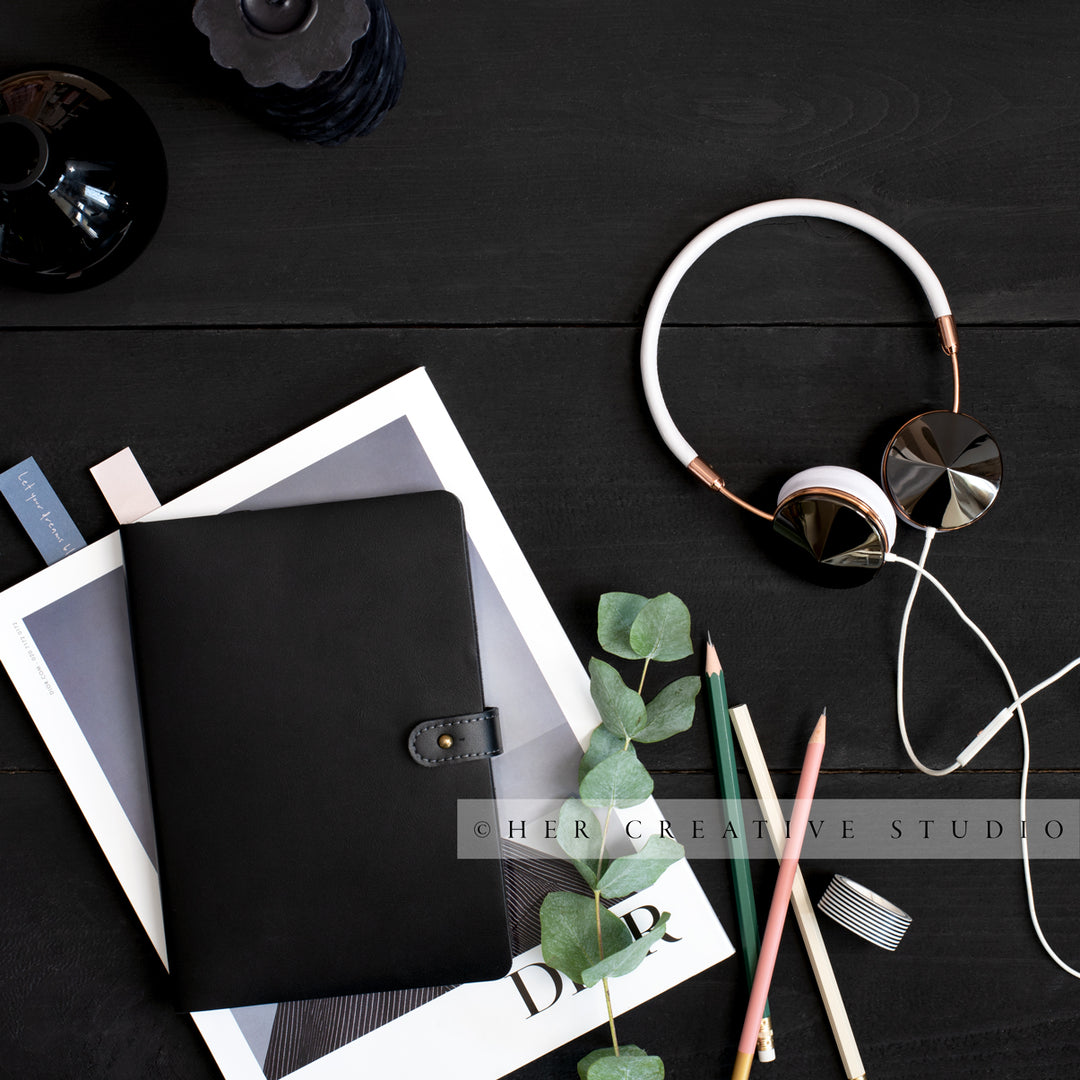 Notebook & Headphones on Black Desk