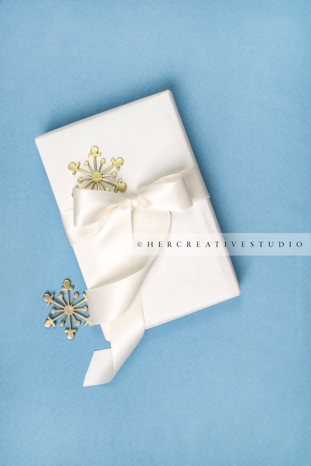 Holiday Gift with Gold Snowflakes on Sky Blue Background